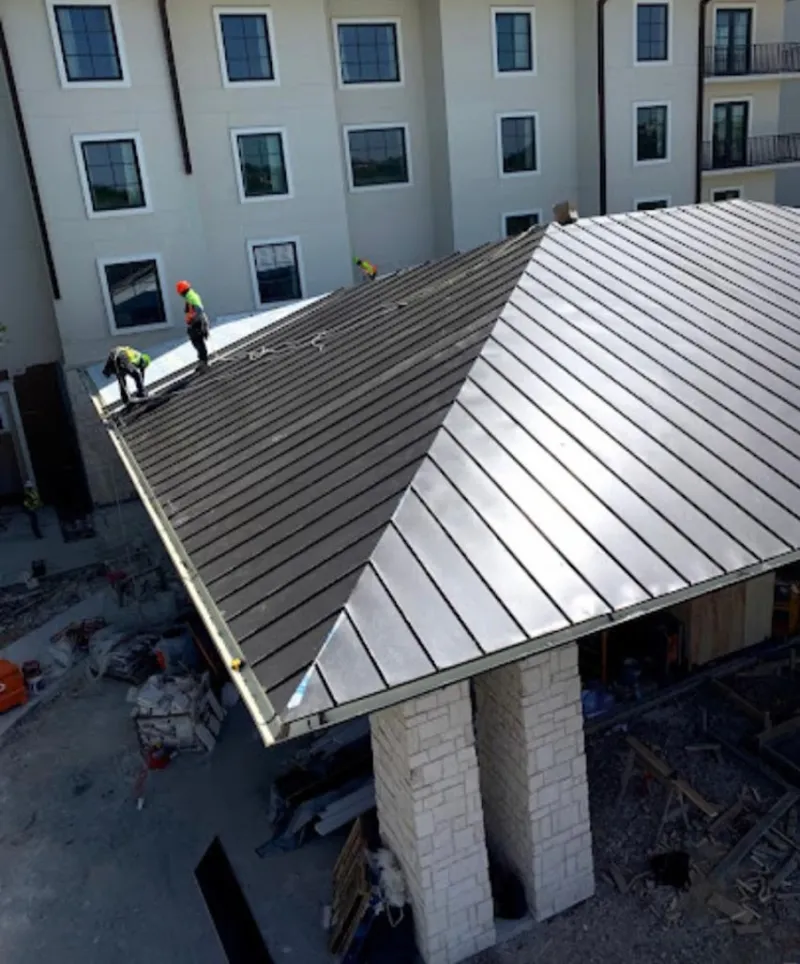 Crew installing standing seam metal roof panels on a commercial project in Southlake